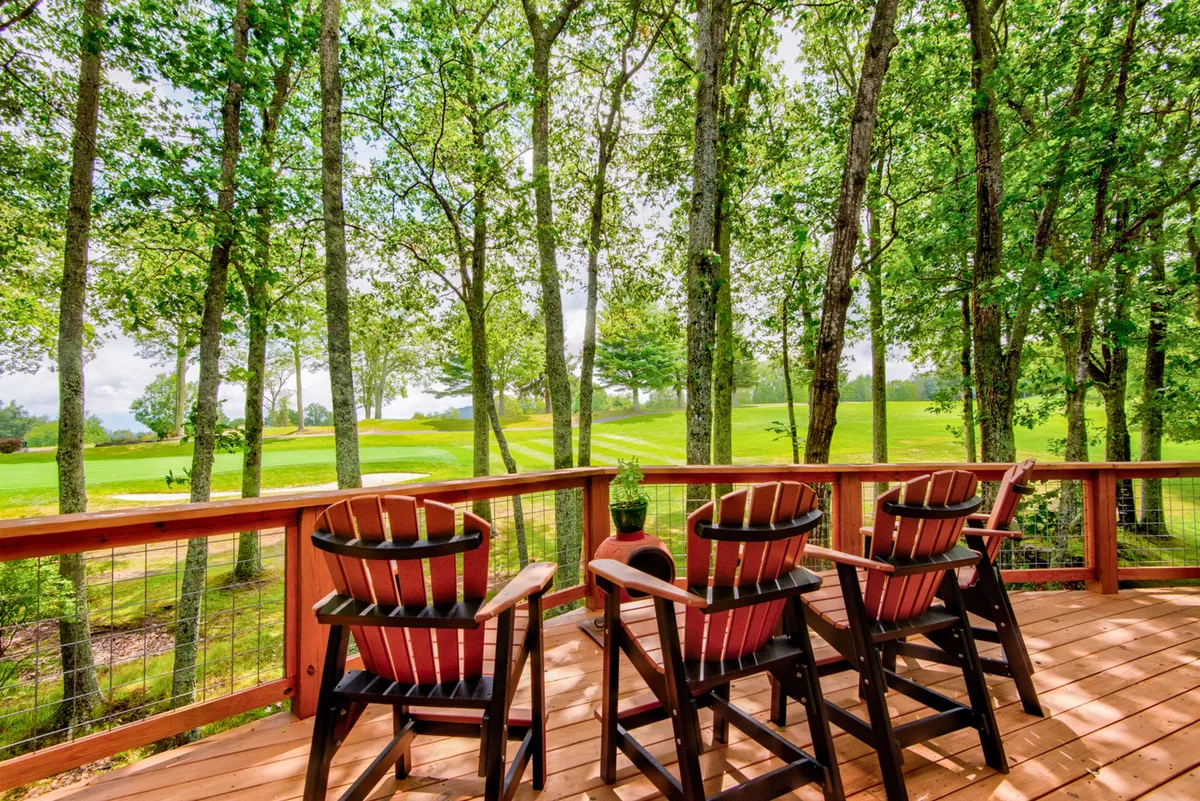 An outdoor setting featuring a group of Adirondack chairs on a deck, facing lush greenery and a distant golf course. The area feels peaceful and social, ideal for enjoying sunsets, wildlife, or gathering after a day of adventure.