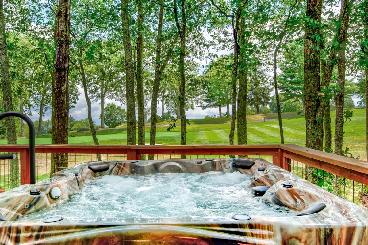 An inviting hot tub set on a deck, overlooking the lush greenery and the golf course beyond. The scene captures the tranquil atmosphere after a day on the course, with space for both relaxation and enjoyment of the natural setting.