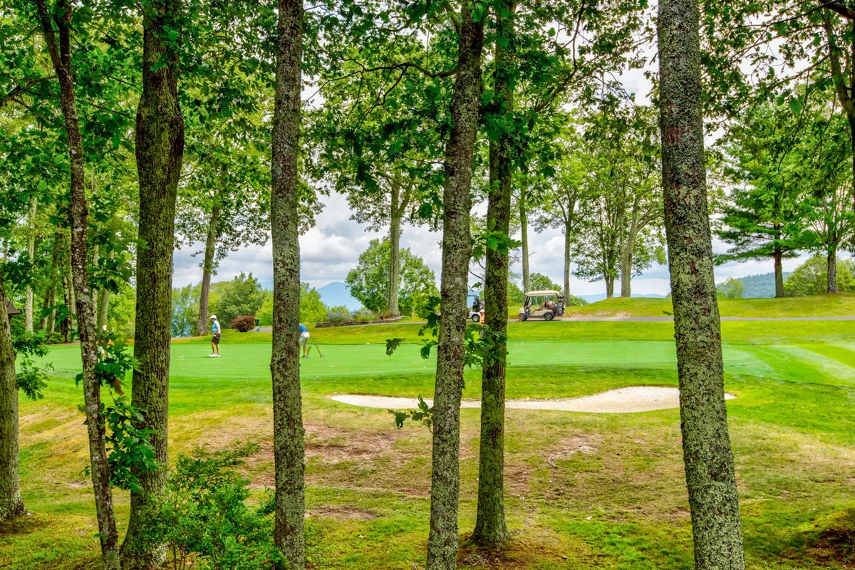 Golfers are in action on the green, with a golf cart nearby and a sand trap in view. The image radiates a sense of camaraderie and activity, showing guests making the most of the course just steps from the property.